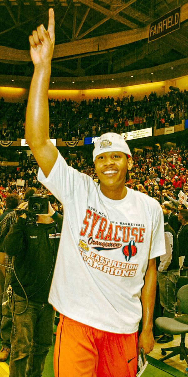 a man standing on top of a basketball court holding his hand up in the air