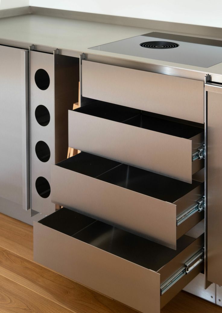 an open drawer in the side of a stainless steel cabinet with drawers on each side