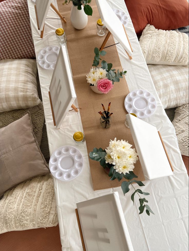 the table is set up with flowers and plates on it, along with other decorations