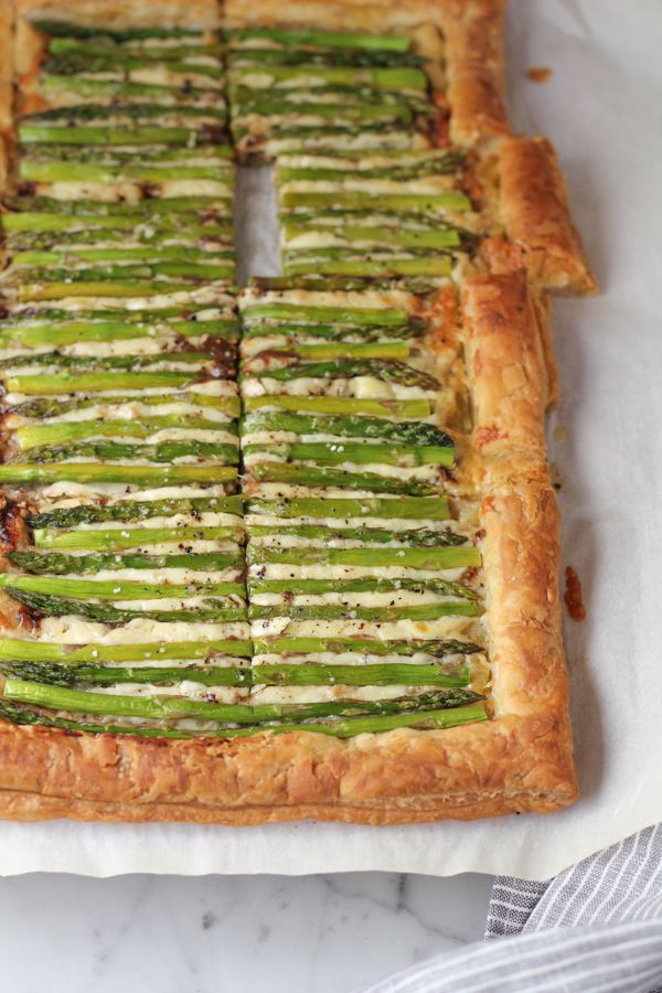 asparagus and cheese tart on top of a white tablecloth with wooden utensils