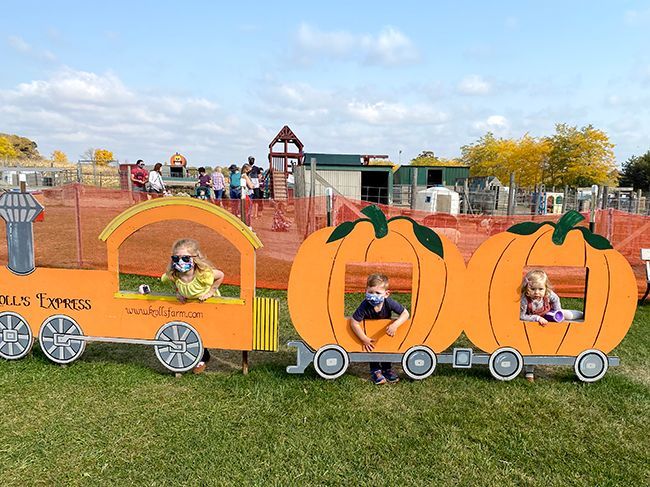 two children are sitting in a pumpkin shaped train