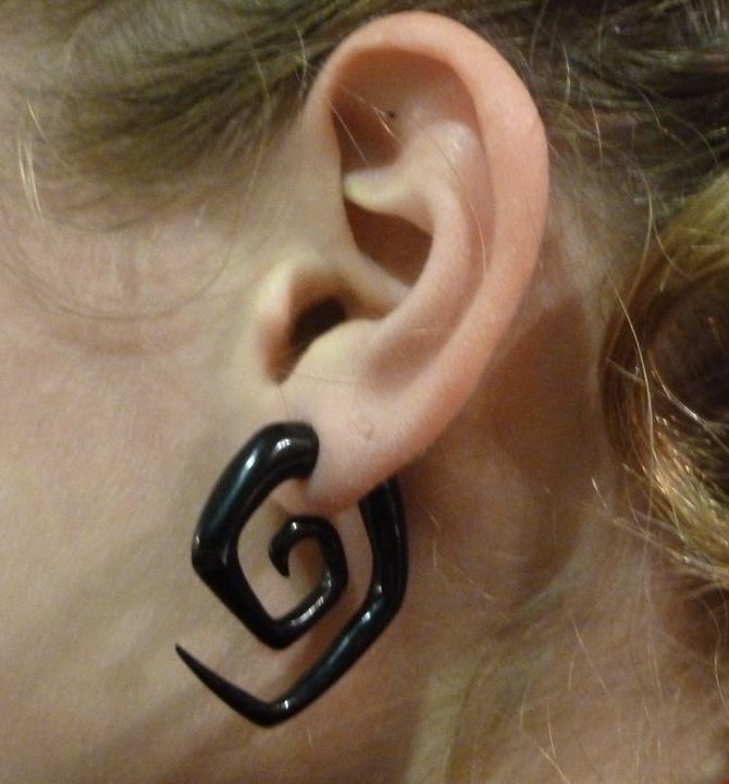 a close up of a person's ear with an ear clip in the shape of a spiral