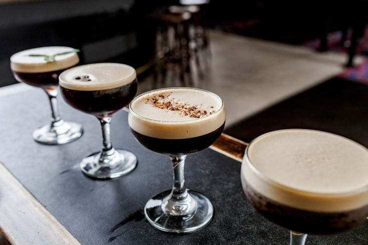 three different types of drinks sitting on a table next to each other in wine glasses