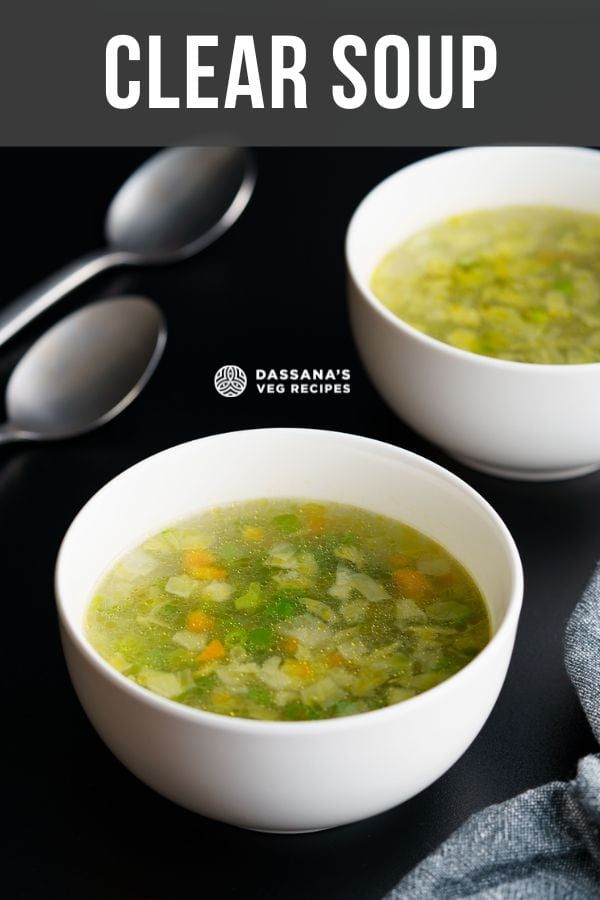 two white bowls filled with soup on top of a black table next to spoons