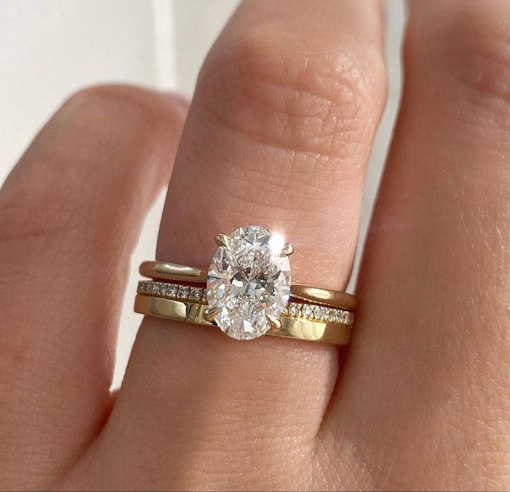 a woman's hand with a gold ring and a diamond engagement ring on it