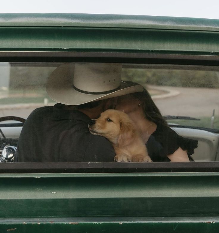 a dog is sitting in the driver's seat of a green truck with a cowboy hat on