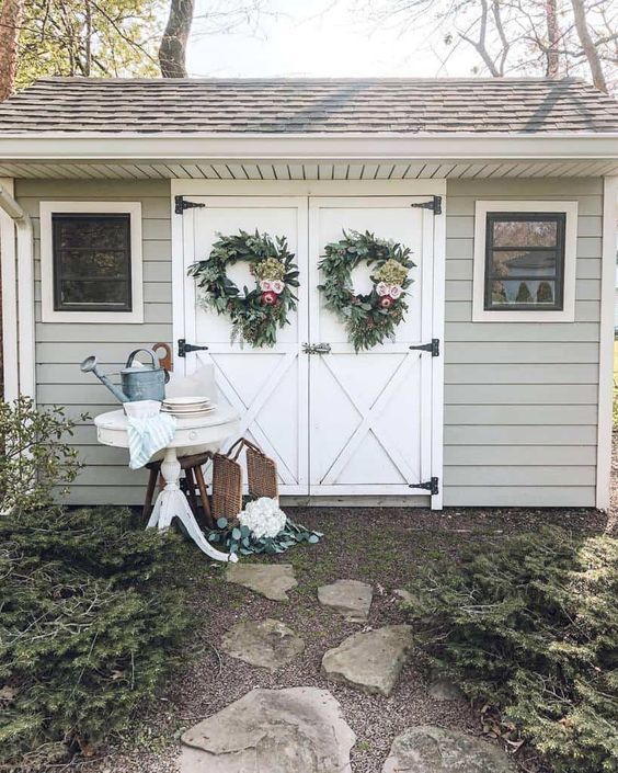 a white shed with wreaths on the doors