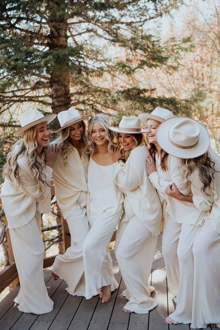 a group of women in white dresses and hats posing for a photo on a deck