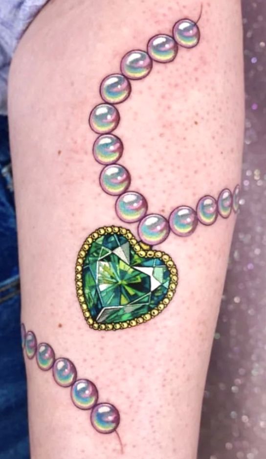 a close up of a person's arm with beads and a heart on it