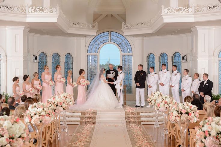 a bride and groom standing in front of their wedding party at the end of an aisle