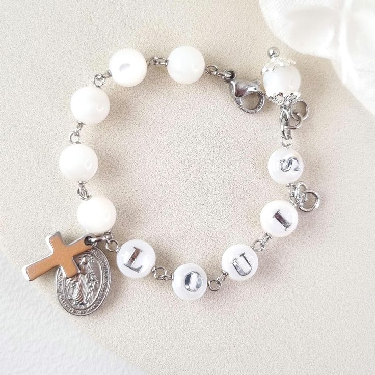 This stunning Baptism bracelet is a truly divine piece that combines elegance and spiritual significance. Crafted with natural mother of pearl beads, it features gold plated virgin Mary and cross charms that symbolize protection and faith. The bracelet is personalized with a handcrafted initial letter, adding a unique touch to this meaningful piece. Perfect for commemorating a special occasion or as a thoughtful gift, this bracelet is a beautiful reminder of faith and blessings. *MATCHING ROSARY PRAYER: https://www.etsy.com/au/listing/1492666531/personalized-rosary-beads-pearl-rosary *Materials:  High Quality 18k gold plated Stainless Steel charms * Gemstone: Genuine mother of pearl beads, round shape, 6mm * Closure: adjustable finial, lobster clasp * Letter beads: handmade, mother of pear Pearl Charm Mother Of Pearl Bracelets As Gift, Mother Of Pearl Bracelets For Gifts, Mother Of Pearl Bracelets With Round Beads For Gift, Mother Of Pearl Bracelets With Round Beads As Gift, White Spiritual Pearl Bracelet For Gift, Spiritual White Pearl Bracelet Gift, Spiritual White Mother Of Pearl Jewelry, Adjustable Mother Of Pearl Bracelet As Gift, Adjustable Mother Of Pearl Bracelets As Gifts