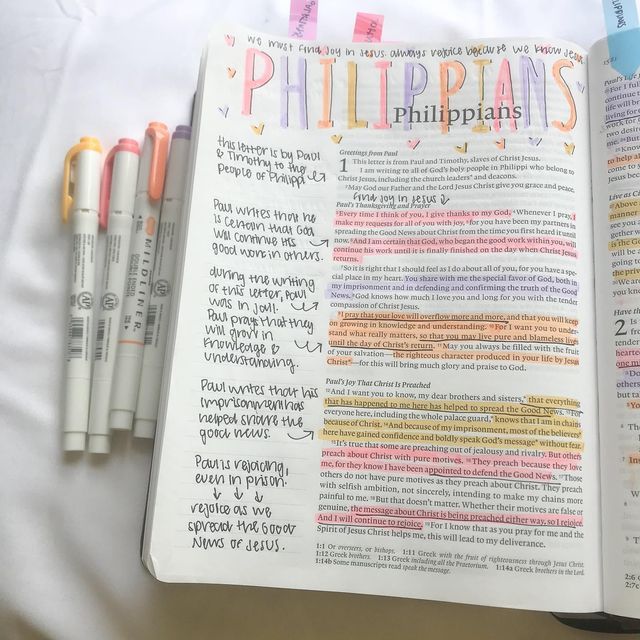 an open bible with writing on it next to four markers and pens in the pages