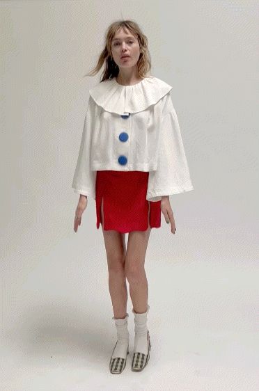 a woman is standing in front of a white background wearing a red skirt and jacket