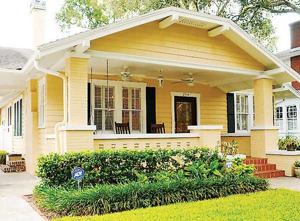 a yellow house with white trim and black shutters on the front door is shown