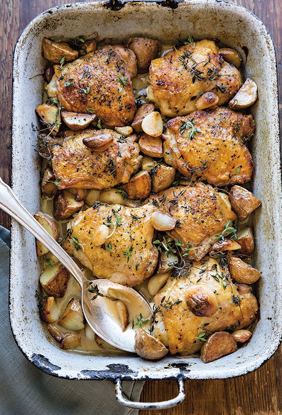 a casserole dish with chicken, potatoes and mushrooms in it on a wooden table