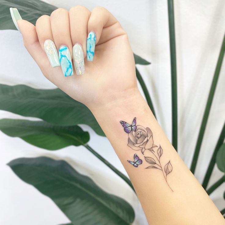 a woman's arm with a rose and butterfly tattoo on the left side of her wrist