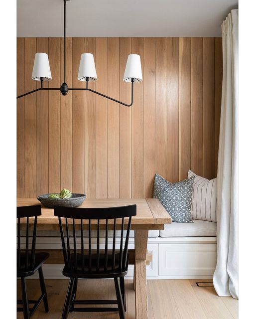 a dining room with wooden paneling and white lamps hanging from the ceiling above it