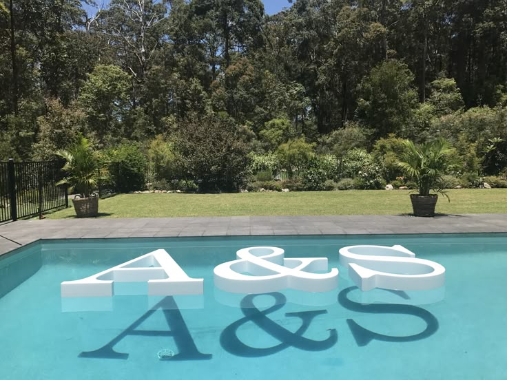 an outdoor swimming pool with the number forty and 45 on it's side, surrounded by trees