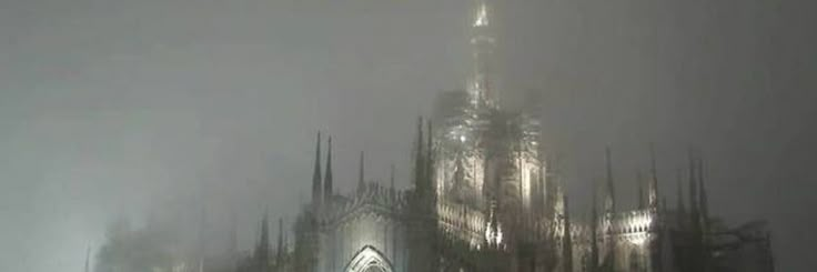 a very tall cathedral towering over a city in the fog