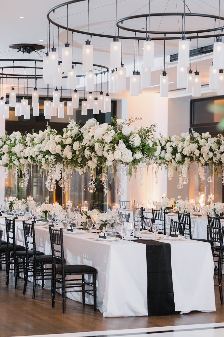 the tables are set with white and black linens, centerpieces, and flowers