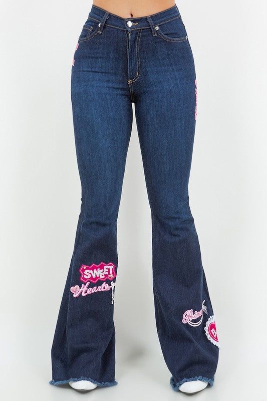 Upgrade your denim wardrobe with our Sweetheart Bell Bottom Jean in Dark Denim! These trendy jeans feature a flattering design with a front button and zipper closure, convenient front and back pockets, and adorable patch and charm accents. Made with premium fabrics in the USA, you can rely on their high-quality.DRY CLEAN ONLY. Silhouette: Bell bottom Fit: High Rise Embellishment: Patches, charms Length: Full Length Closure: button, zipper Made In: USA Fabric Contents: 98% Cotton, 2% Spandex Stre Trendy Medium Wash Flare Jeans With Zipper Closure, Trendy Medium Wash Flare Jeans With Zipper, Dark Wash Denim Flare Jeans With Zipper Closure, Dark Wash Denim Flare Jeans With Zipper, Chic Denim Jeans With Zipper Closure, Trendy Cotton Jeans With Zipper Closure, Spring Denim Blue Flare Jeans With Zipper, Spring Flare Jeans With Zipper Closure In Denim Blue, Spring Flare Jeans In Denim Blue With Zipper