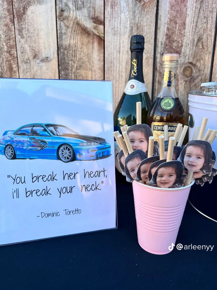 a table topped with cups filled with drinks and photos next to a sign that says you break her heart, i'll break your neck