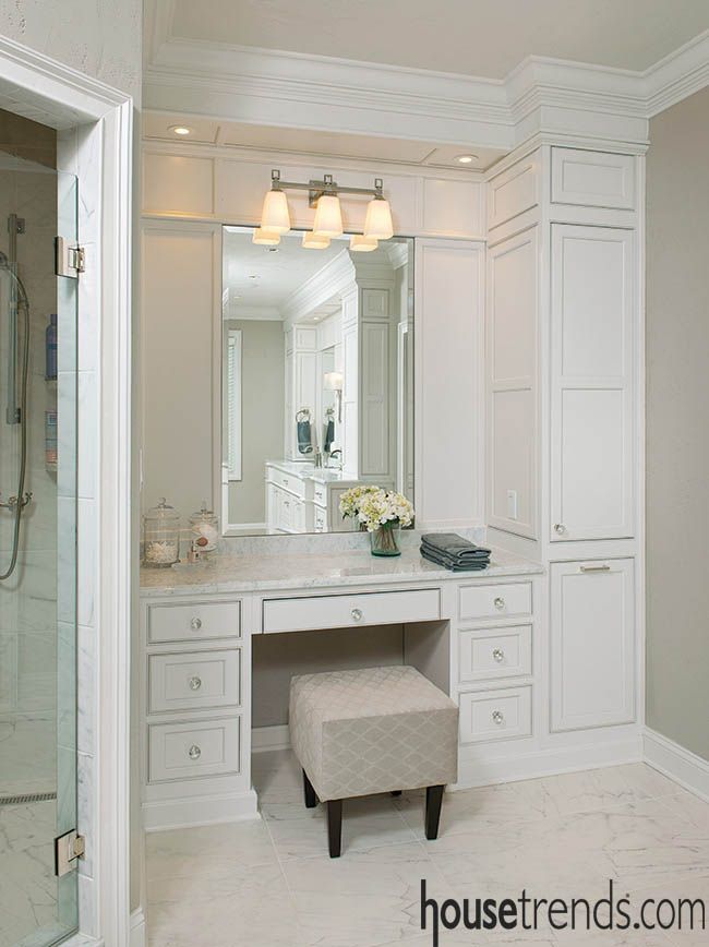 a large bathroom with white cabinets and marble counter tops, along with a bench in front of the mirror