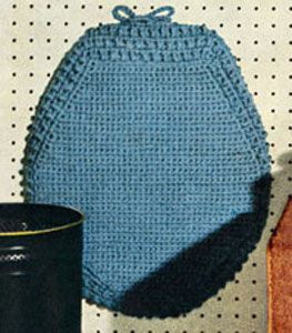 a blue crocheted bag sitting next to a black cup on top of a table