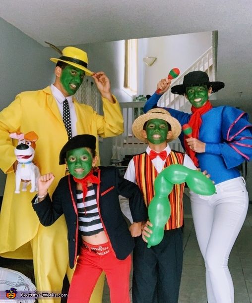 four people dressed in costumes posing for a photo with one holding a balloon and the other wearing a green mask