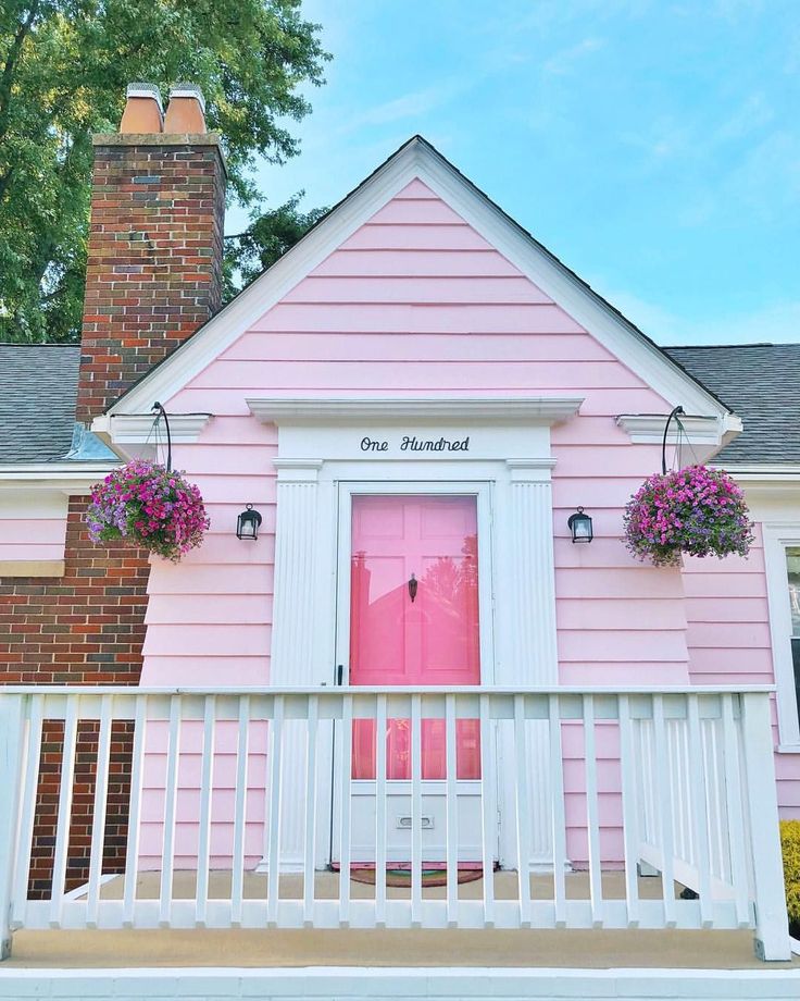 a pink house with flowers on the porch