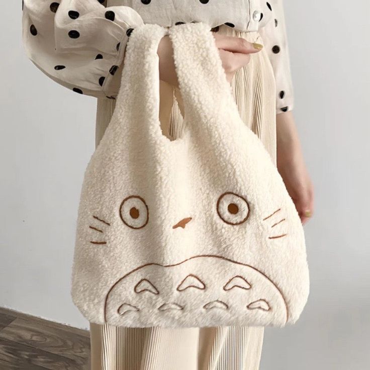 Introducing our My Neighbor Totoro Tote Bag – the epitome of softness and adorableness! Totoro's friendly face is skillfully embroidered on the front, ready to accompany you on your daily adventures. This compact tote is designed to carry your essentials with ease, making it the perfect companion for outings with friends. Available in both white and brown, you can choose the hue that suits your style. Whether you're strolling through the city or meeting up with pals, let Totoro's charm and your Totoro Tote Bag, Totoro Bag, Fabric Handbags, Plush Bags, Handbag Outfit, Fabric Purses, My Neighbor Totoro, Tote Pattern, Hanging Bag