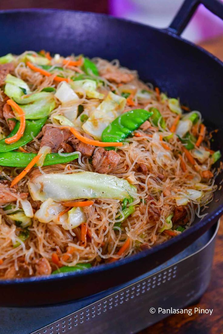 a pan filled with noodles and vegetables on top of a table