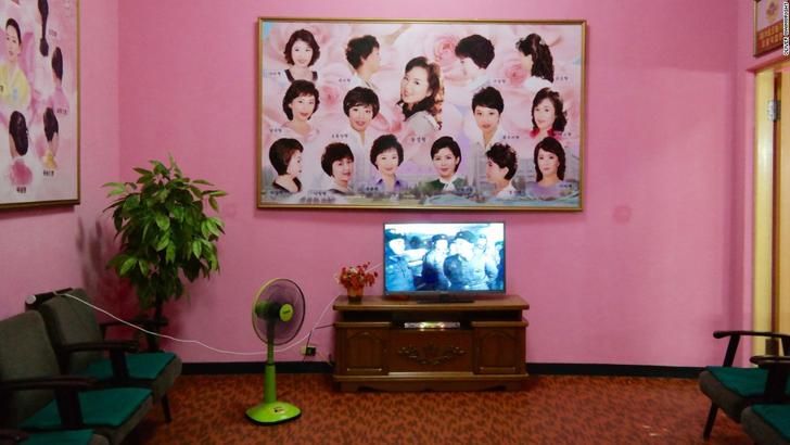 a living room with pink walls and pictures on the wall