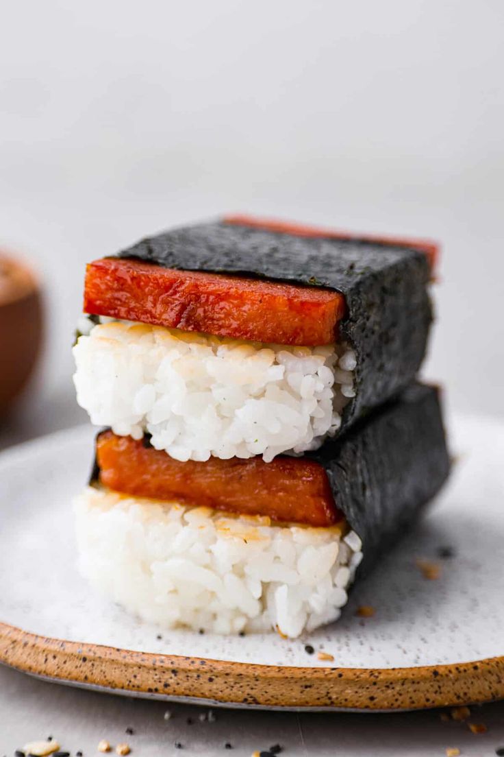 three pieces of sushi stacked on top of each other with white rice and sauce