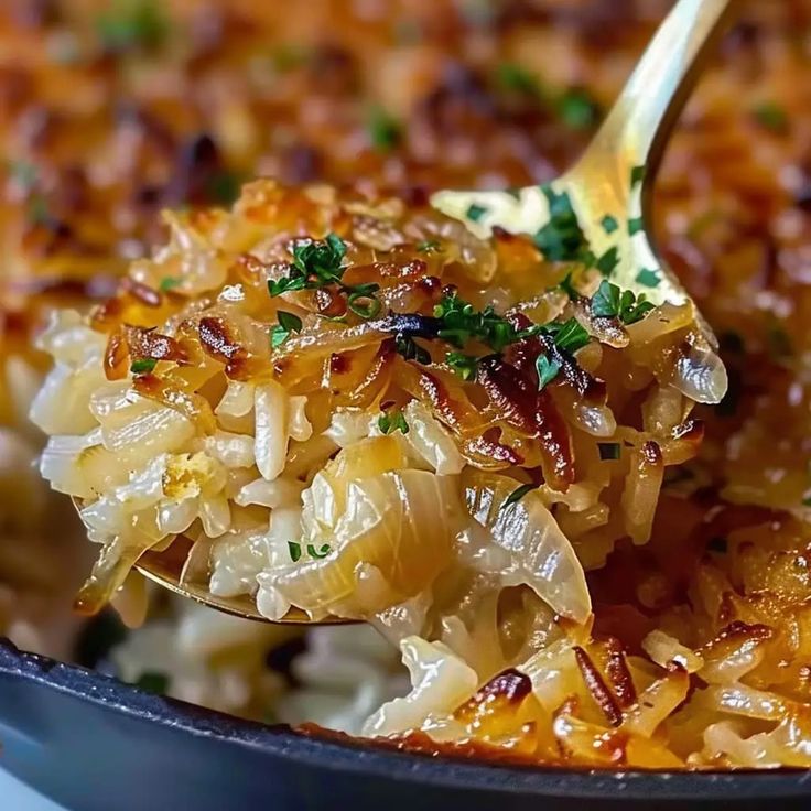 a close up of a spoon full of food with onions and cheese on it's side