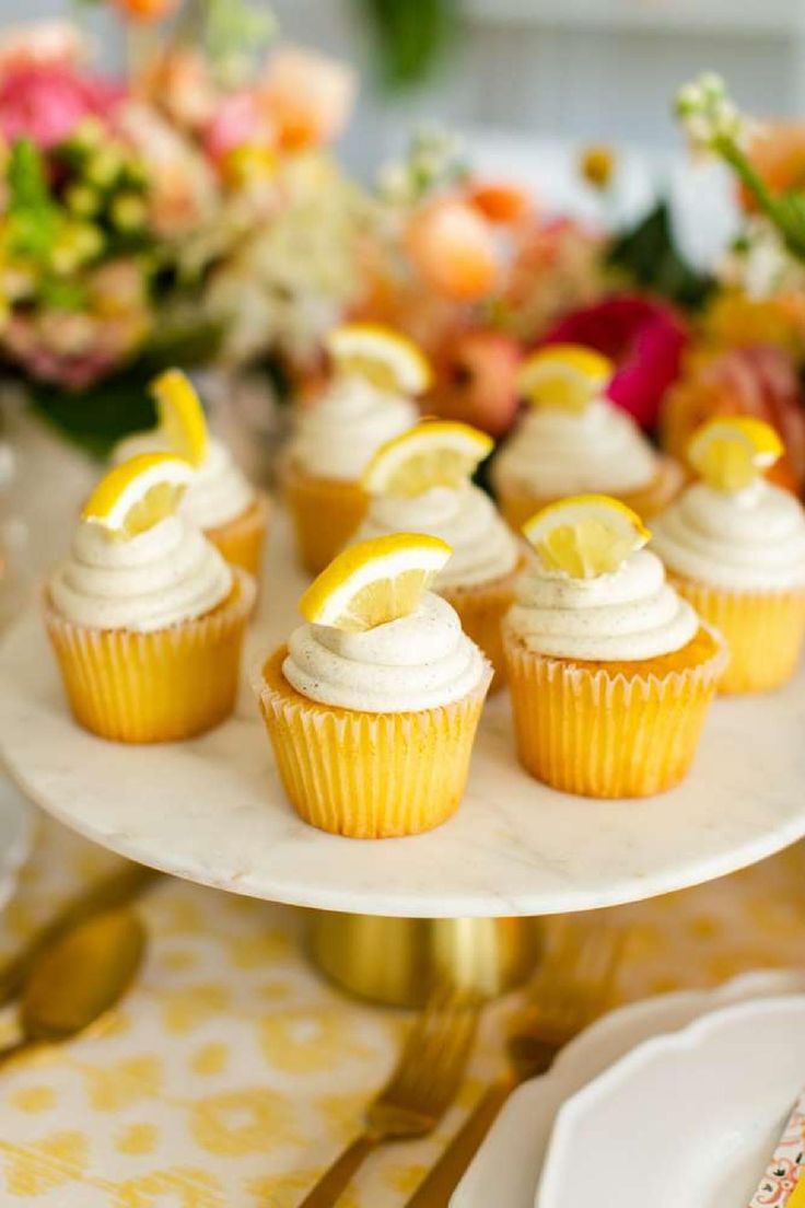 cupcakes with lemon slices and white frosting on a cake stand