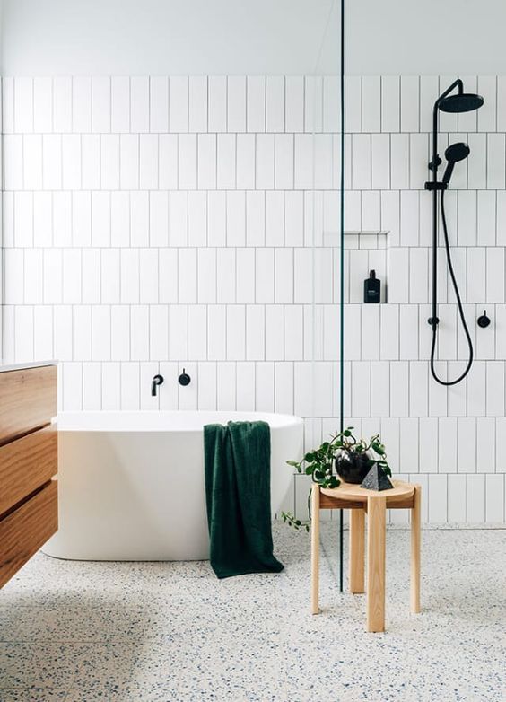 a bath tub sitting next to a wooden table in front of a white tiled wall