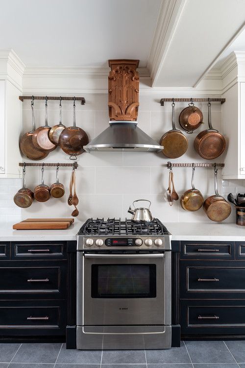 a stove top oven sitting inside of a kitchen next to wooden spoons and pans