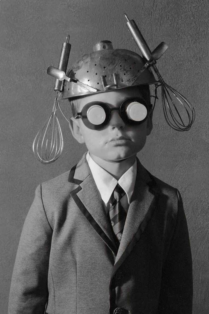 a black and white photo of a little boy wearing a hat with goggles on his head