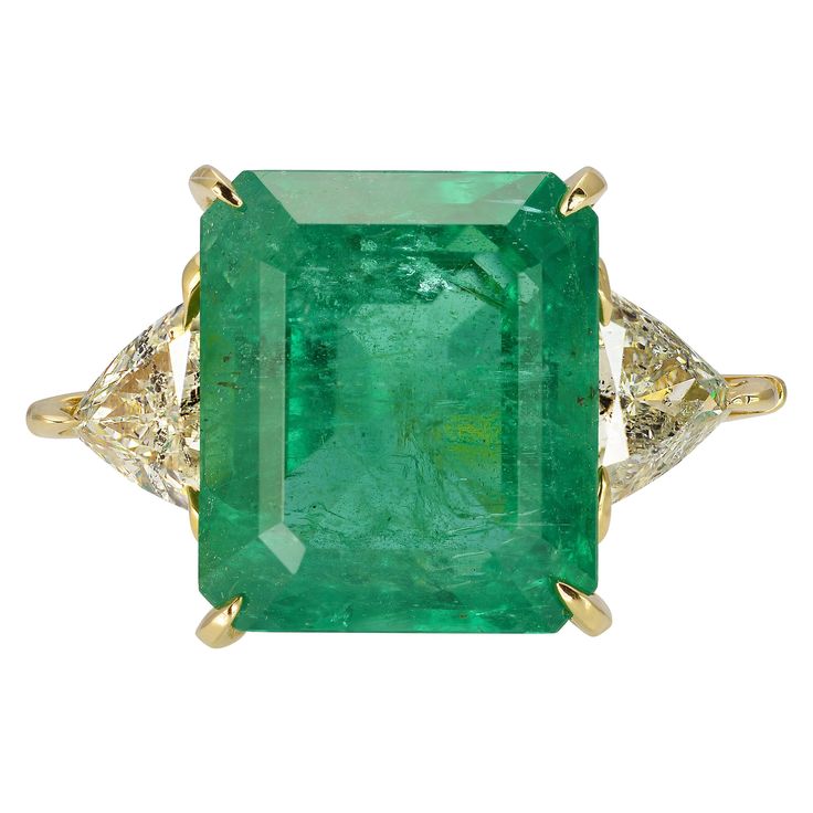 18 Karat Yellow Gold Three Stone Cocktail Ring Featuring A 10 Carat Emerald GIA Graded As Zambian In Origin. Two Trilliant Cut Side Diamonds Total 1.40 Carats Of I1 Clarity & H Color. Hidden Hearts in Gallery. Finger Size 6; Purchase Includes One Free Sizing. Emerald Statement Ring, Colombian Emerald Ring, Verdant Green, Contemporary Engagement Rings, Emerald Wedding Rings, Bracelet Love, Platinum Diamond Rings, Emerald Diamond Ring, Zambian Emerald