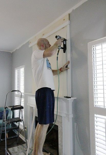 a man using a power drill to paint a fireplace