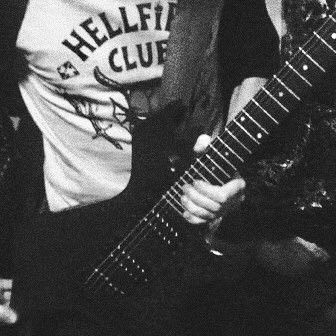 black and white photograph of a man holding a guitar in his right hand while wearing a t - shirt with hellfest club on it