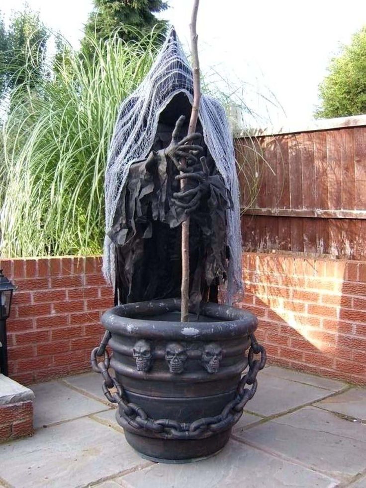 a large black pot with a statue in it on a stone floor next to a brick wall