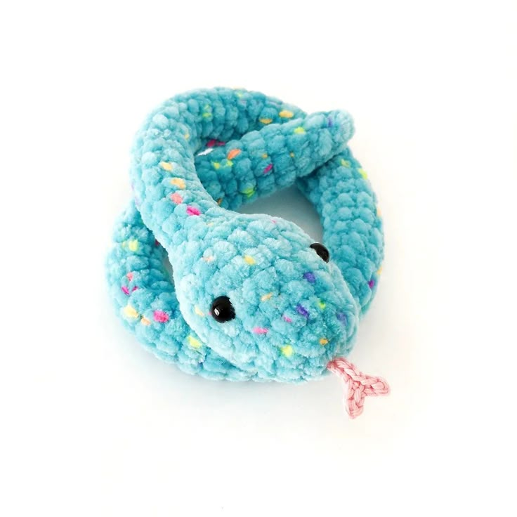 a crocheted rattler with a pink ribbon around it's neck on a white surface