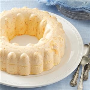 a bundt cake sitting on top of a white plate next to two silver spoons