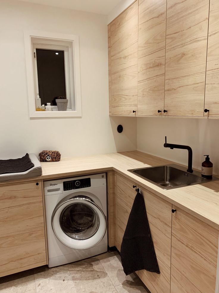 a washer and dryer sitting in a kitchen next to wooden cupboards on the wall