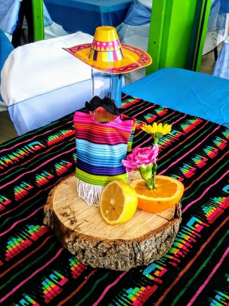 a table topped with an orange slice next to a colorful hat on top of a piece of wood