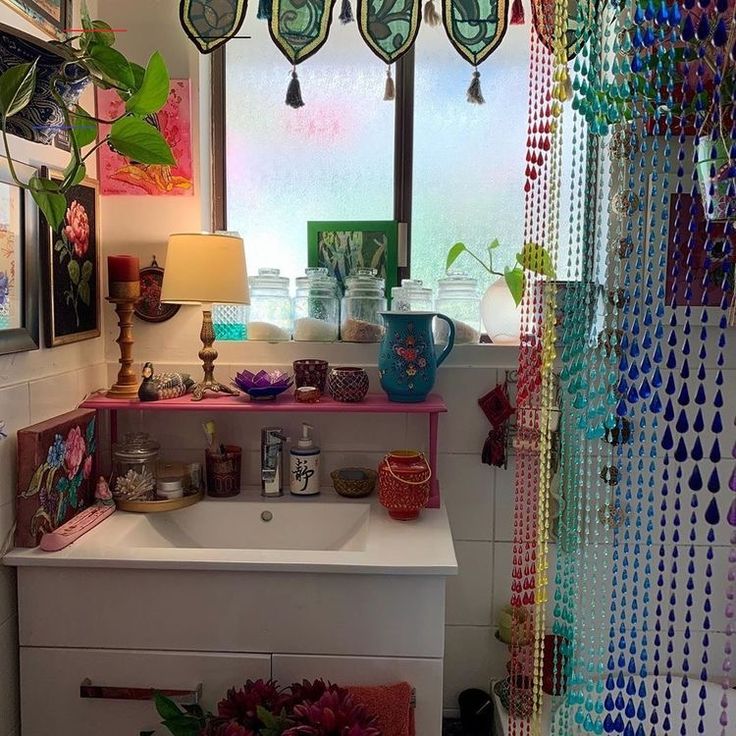 there is a sink in the room with many beads hanging on the wall above it