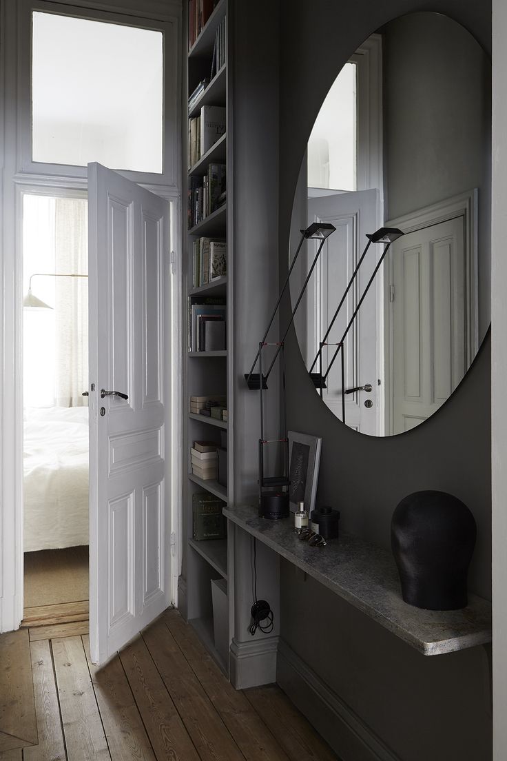 a room with a mirror, bookshelf and shelves