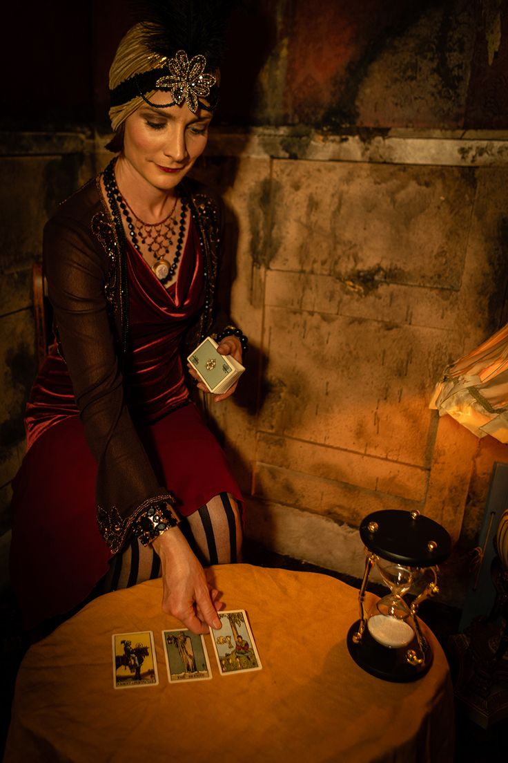 a woman sitting at a table with cards in front of her and a lamp on the side